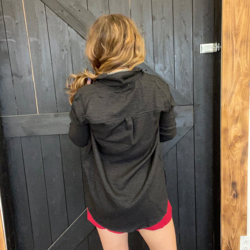 Person wearing a black jacket and red shorts standing in front of a wooden door.