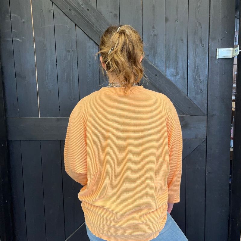 Person wearing a yellow sweater standing in front of a dark wooden door