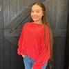 Young girl in a red sweater standing in front of a wooden door