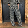 Person wearing a black and white striped outfit standing against a wooden door.