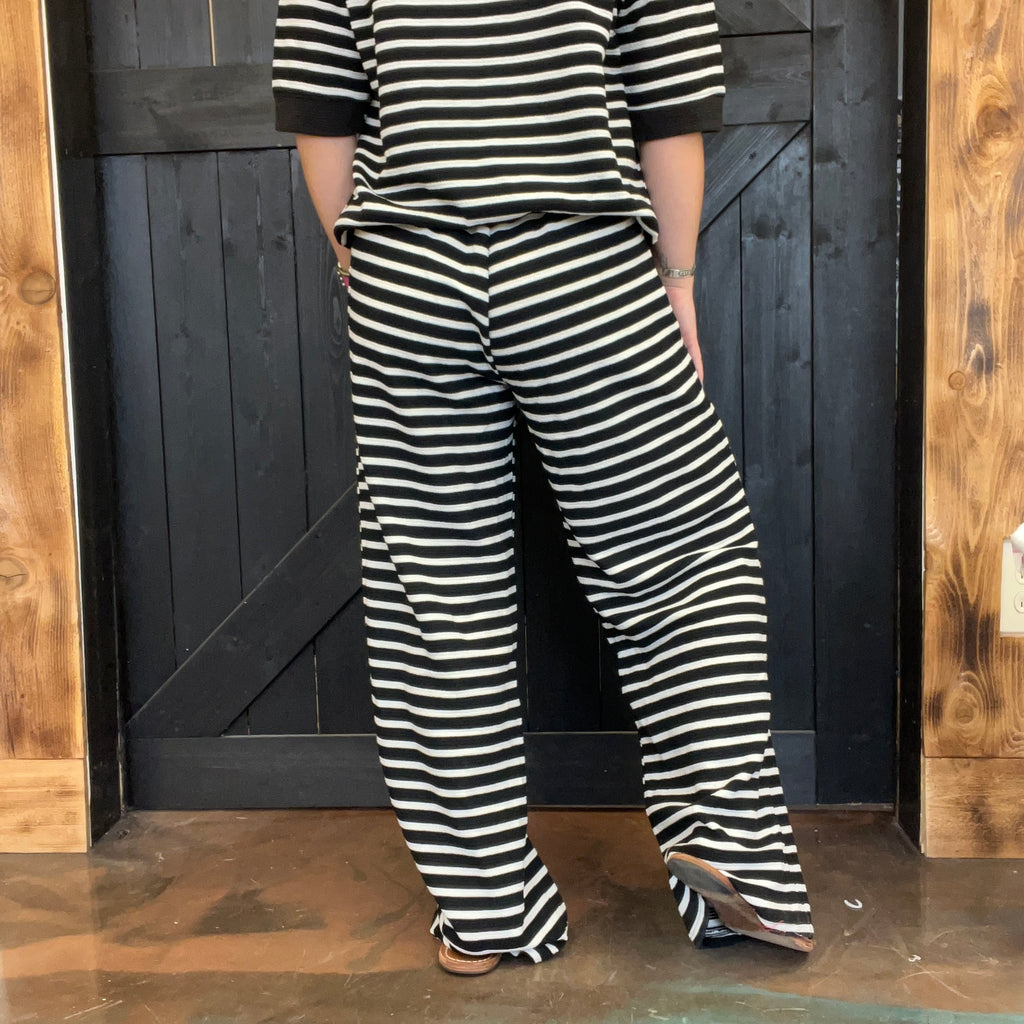 Person wearing a black and white striped outfit standing against a wooden door.