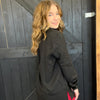Woman wearing a black jacket standing in front of a wooden door