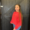 Young girl in a red sweater standing in front of a wooden door