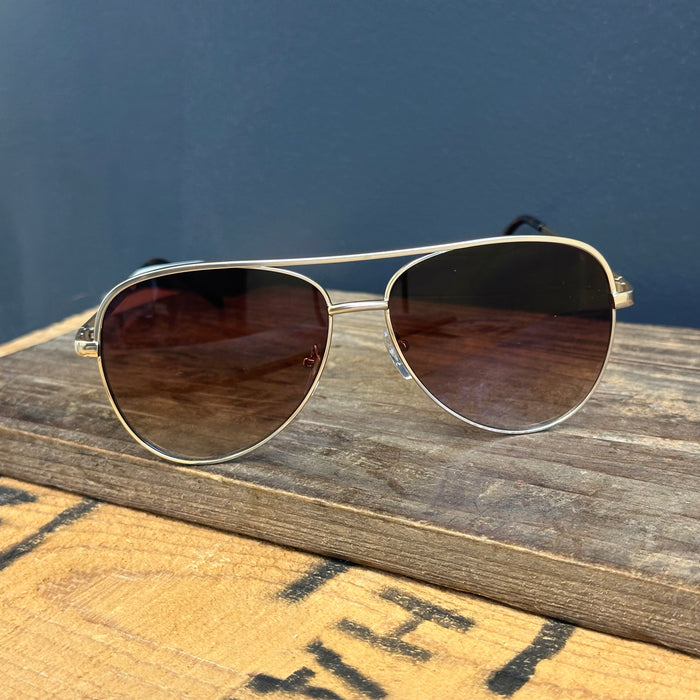 Aviator sunglasses with brown lenses on a wooden surface against a blue background