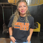 Woman wearing a black t-shirt with orange text in an indoor setting