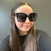 Person wearing large sunglasses with a neutral background