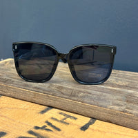 Black sunglasses on a wooden surface with a dark blue background