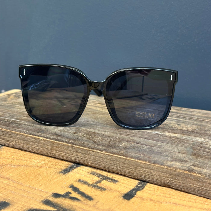 Black sunglasses on a wooden surface with a dark blue background