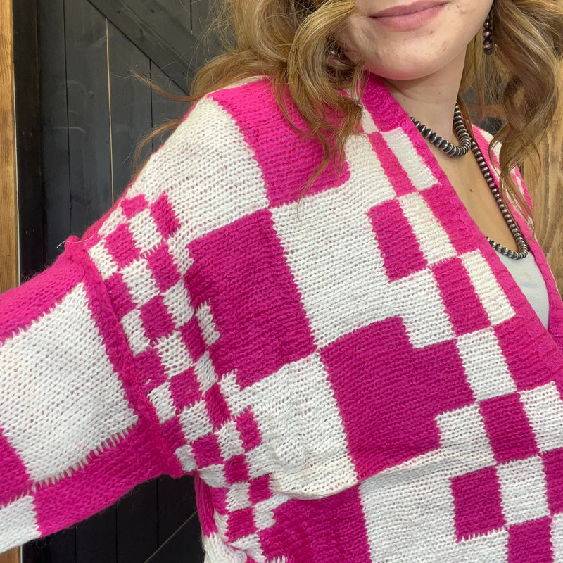 Person wearing a pink and white checkered sweater with a blurred background
