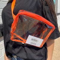 Person wearing a clear pouch with orange trim on a black shirt