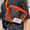 Person wearing a clear pouch with orange trim on a black shirt