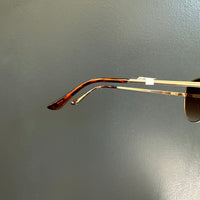 Sunglasses with a gold frame and dark lenses on a gray background
