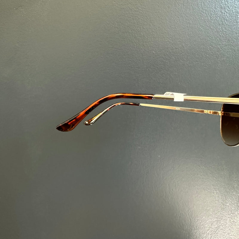 Sunglasses with a gold frame and dark lenses on a gray background