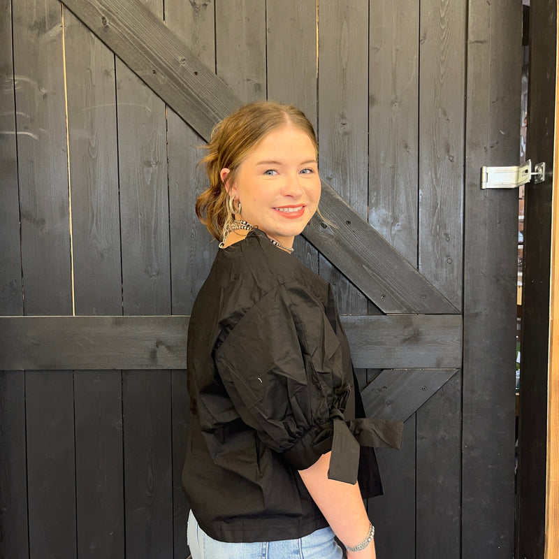 Woman in a black top standing against a wooden door