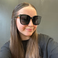 Person wearing large sunglasses with a neutral background