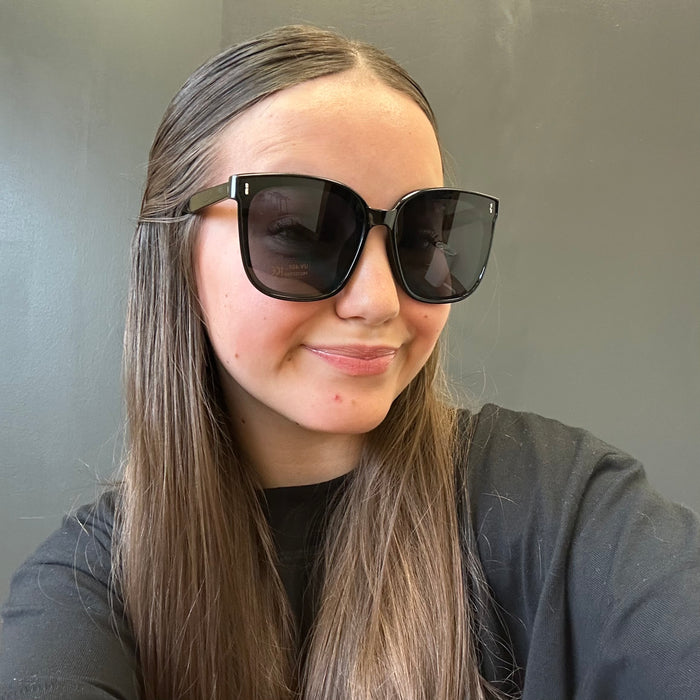 Person wearing large sunglasses with a neutral background