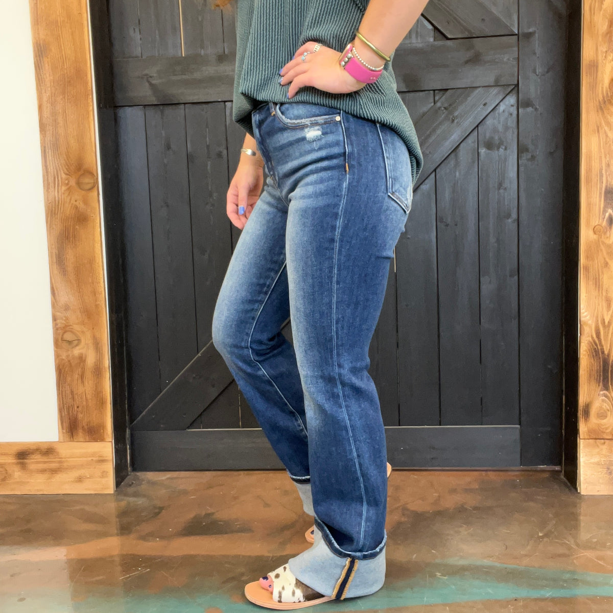 Person wearing blue jeans standing in front of a wooden door.