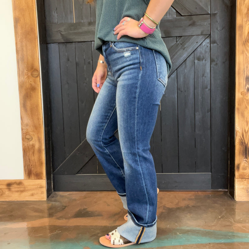 Person wearing blue jeans standing in front of a wooden door.