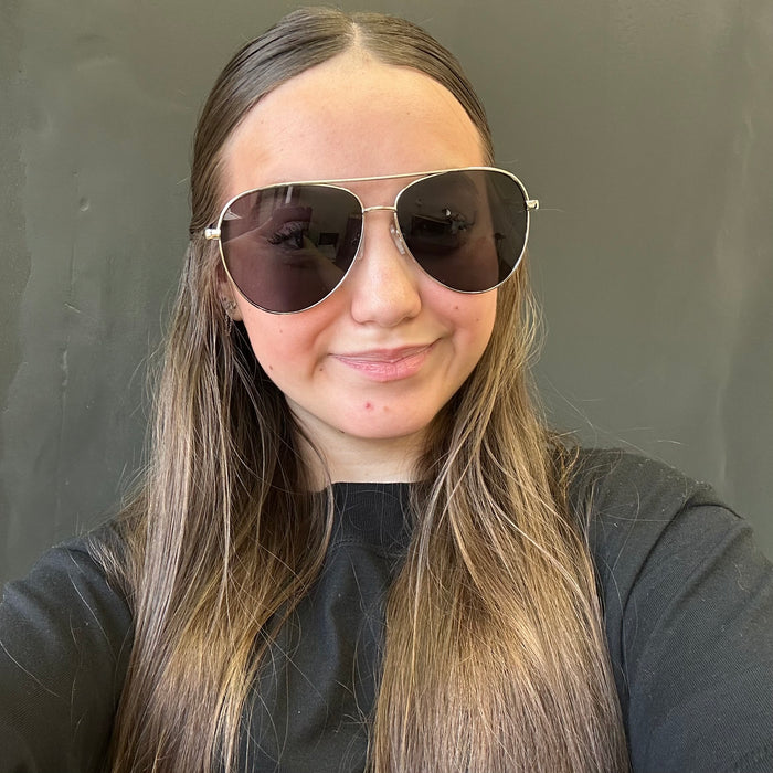 Person wearing aviator sunglasses with a neutral background