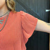 Person wearing a textured orange sweater with a black background