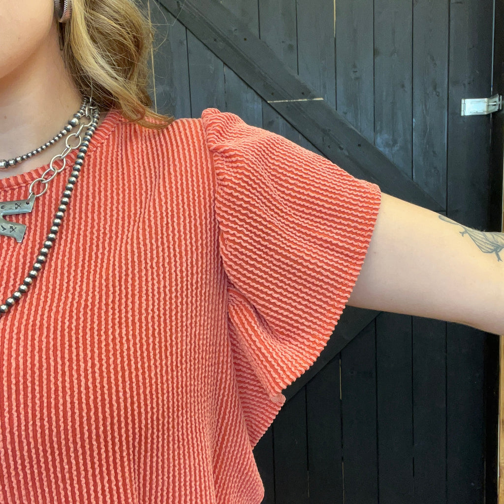 Person wearing a textured orange sweater with a black background