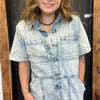 Person wearing a light blue denim dress standing in front of a wooden door.