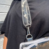Person wearing a clear plastic bag with a strap over their shoulder against a gray wall.