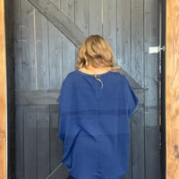 Person wearing a blue sweater standing in front of a wooden door.