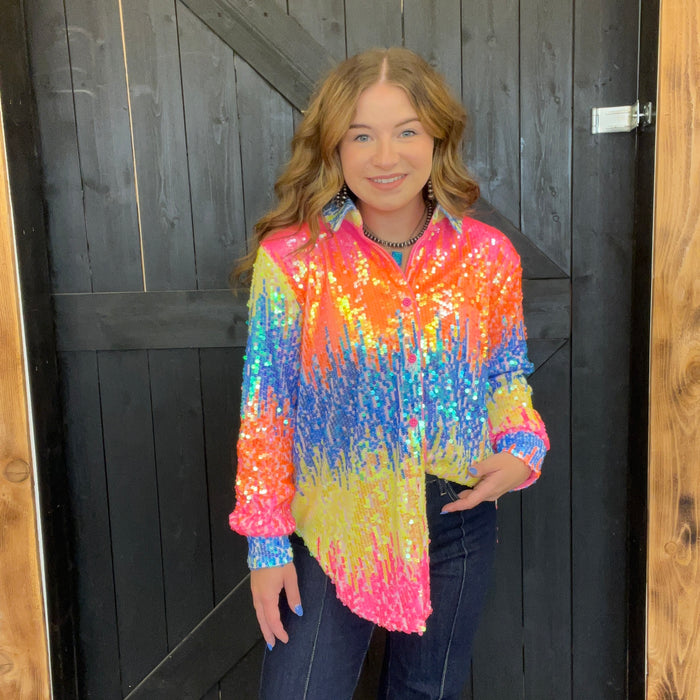 colorful sequin jacket standing in front of a wooden door.