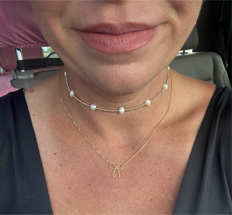 gold necklace with a bow pendant and a pearl necklace.