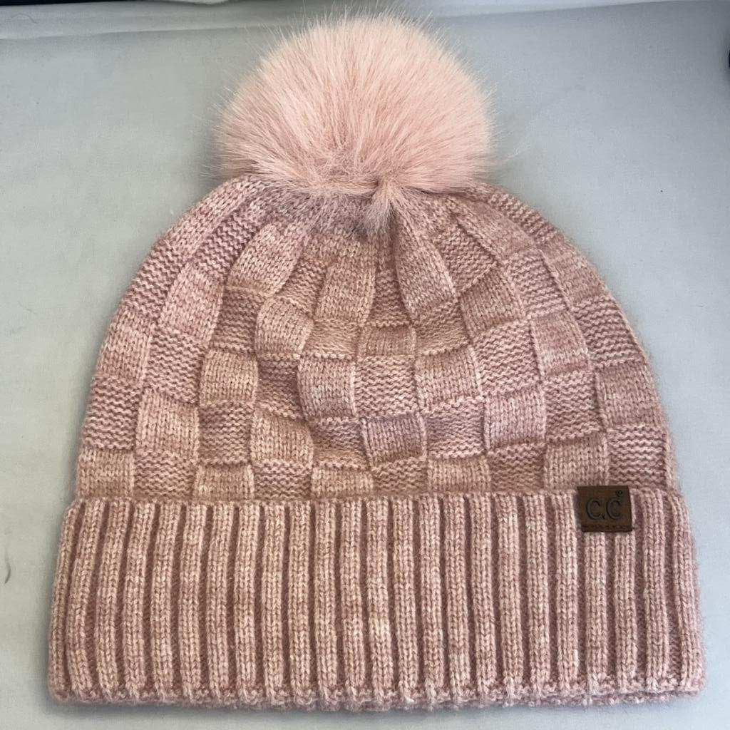 Knitted beanie with a pink pom-pom on a light gray background