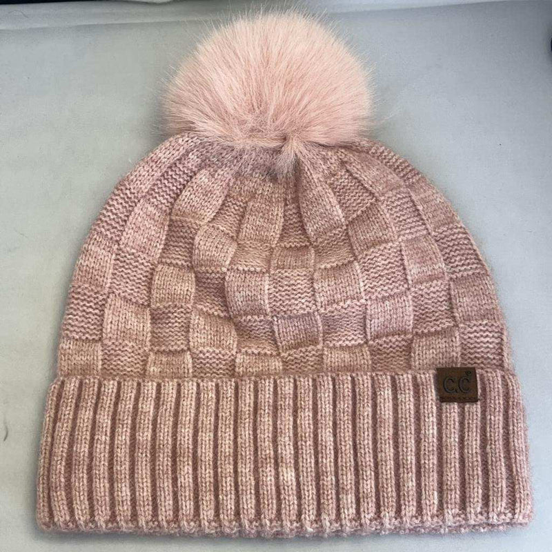 Knitted beanie with a pink pom-pom on a light gray background