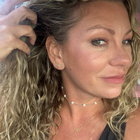 Close-up of a woman with styled hair and jewelry, including earrings and necklaces.