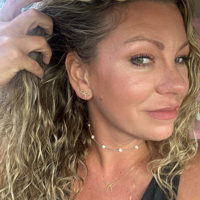 Close-up of a woman with styled hair and jewelry, including earrings and necklaces.