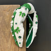 Decorative headband with green and white design on a wooden block against a black background