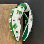 Decorative headband with green and white design on a wooden block against a black background