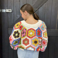  colorful crochet sweater with a geometric pattern against a wooden door.