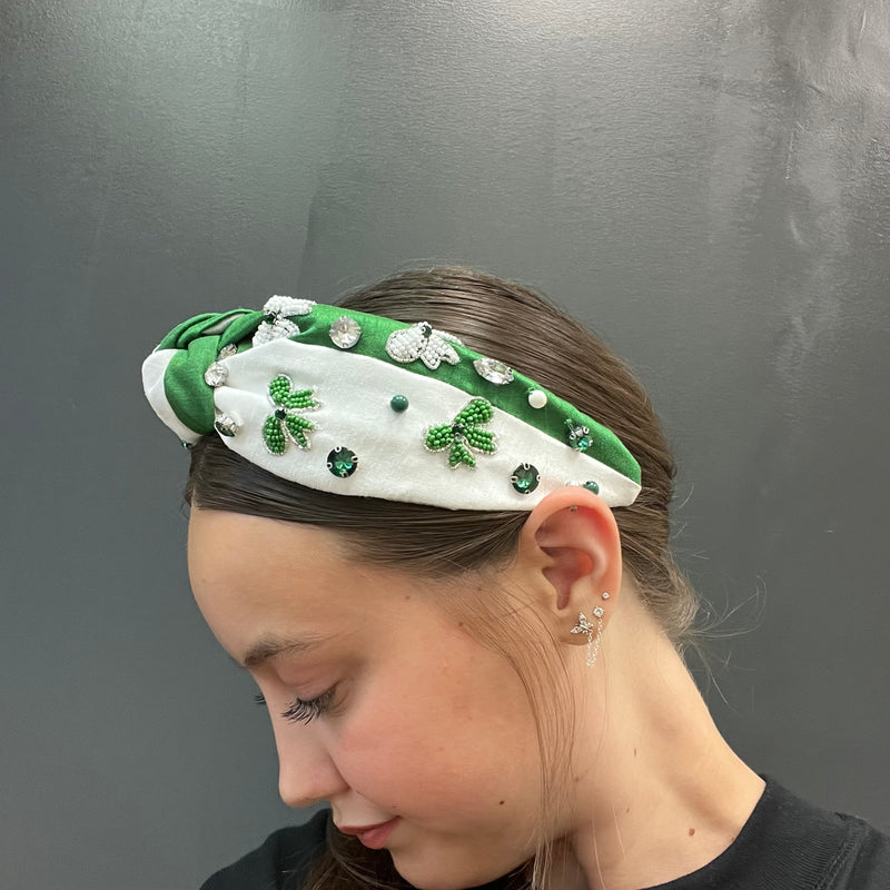 Woman wearing a green and white headband with decorative elements on a gray background