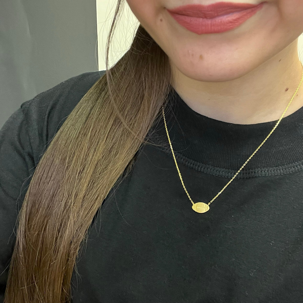 Close-up of a person wearing a gold necklace with a black shirt.