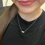 Close-up of a person wearing a delicate necklace with a black shirt.