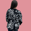 Person wearing a black sweater with white floral patterns against a plain background