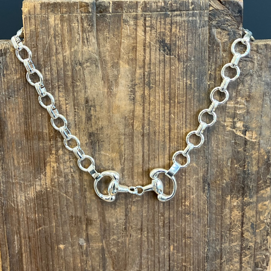 Silver chain necklace on a wooden block with a dark background