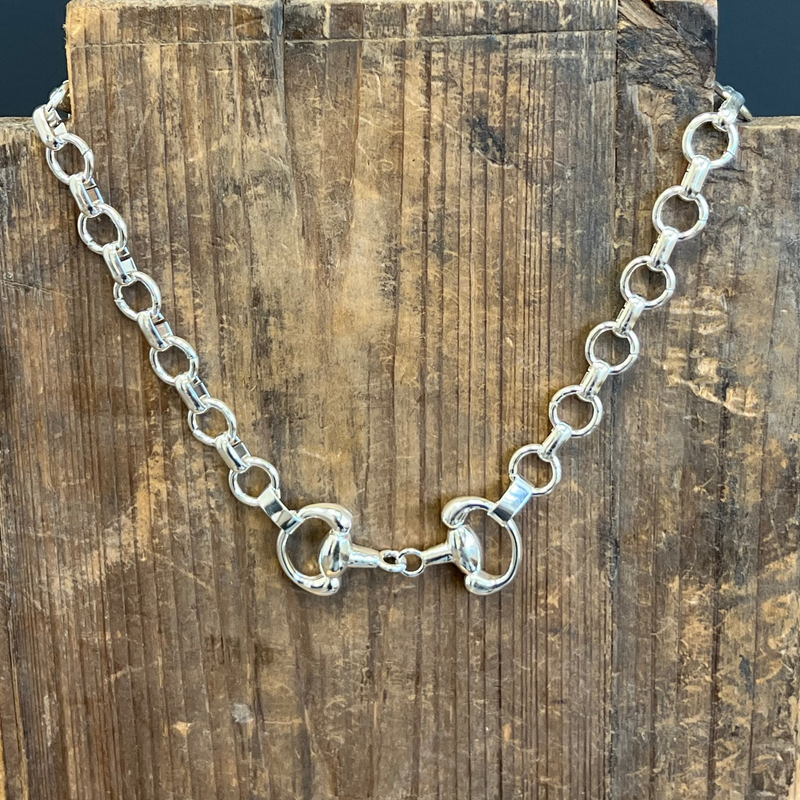 Silver chain necklace on a wooden block with a dark background