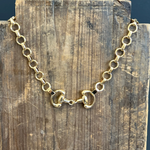 Gold chain necklace on a wooden block with a dark blue background
