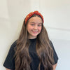 Young girl wearing a decorative headband against a plain background