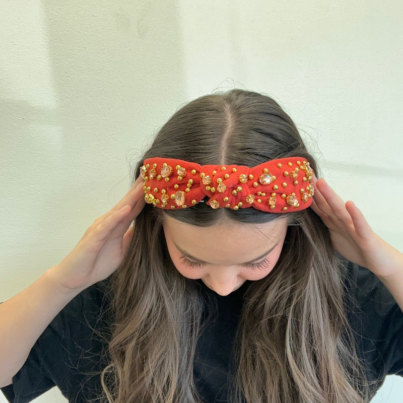 Person wearing a red headband with gold embellishments on a white background