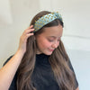Girl wearing a light blue headband with gold studs against a white background