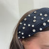 Navy blue headband with pearls and crystals on a plain background