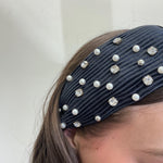 Navy blue headband with pearls and crystals on a plain background