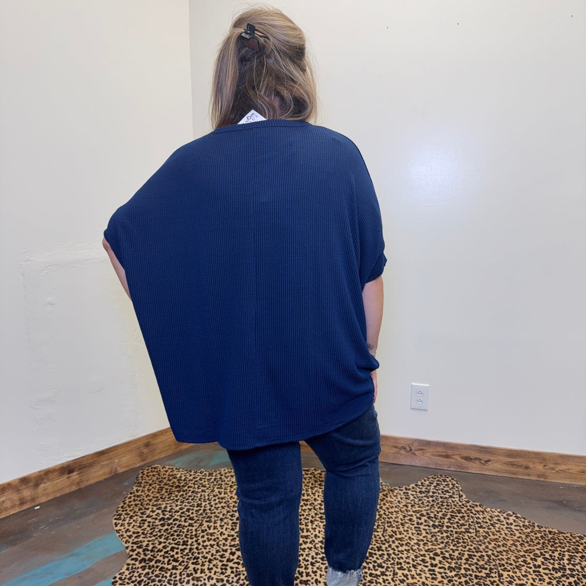 blue sweater and jeans standing in a room with a leopard print rug.